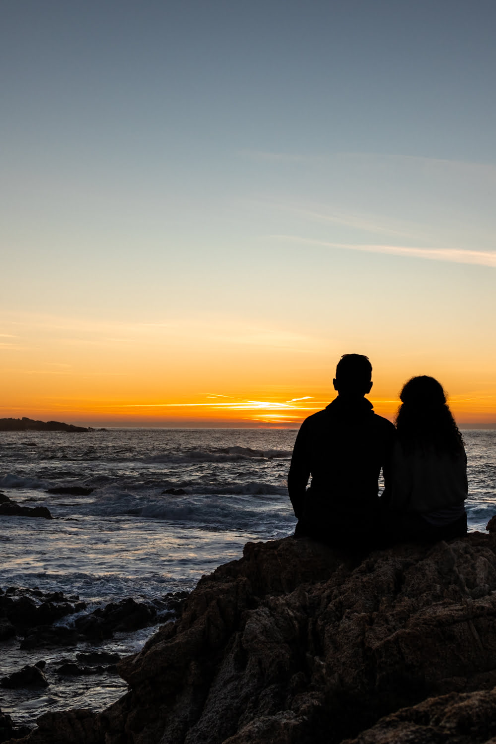 couple qui regarde le coucher de soleil sur la mer