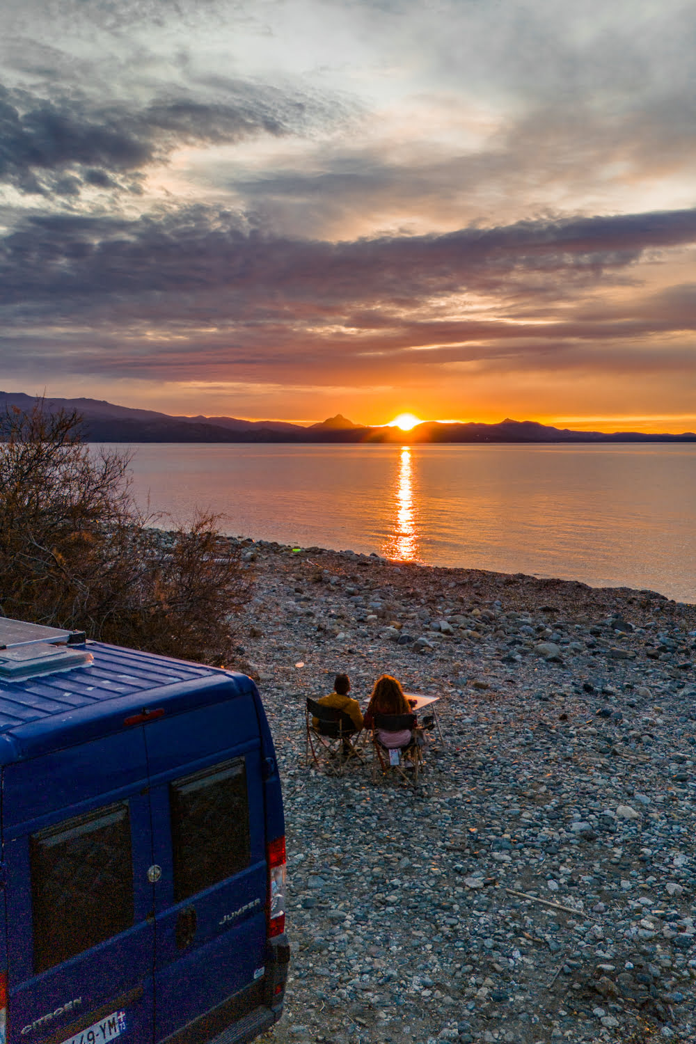 coucher de soleil avec un fourgon aménagé et un couple vue sur la mer