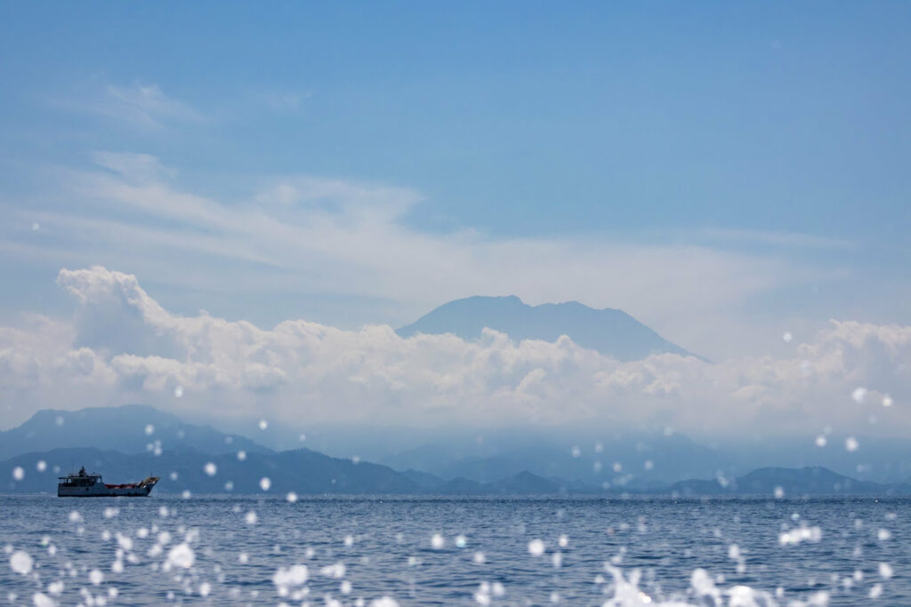 sommet au dessus des nuage depuis l'océan avec un bateau