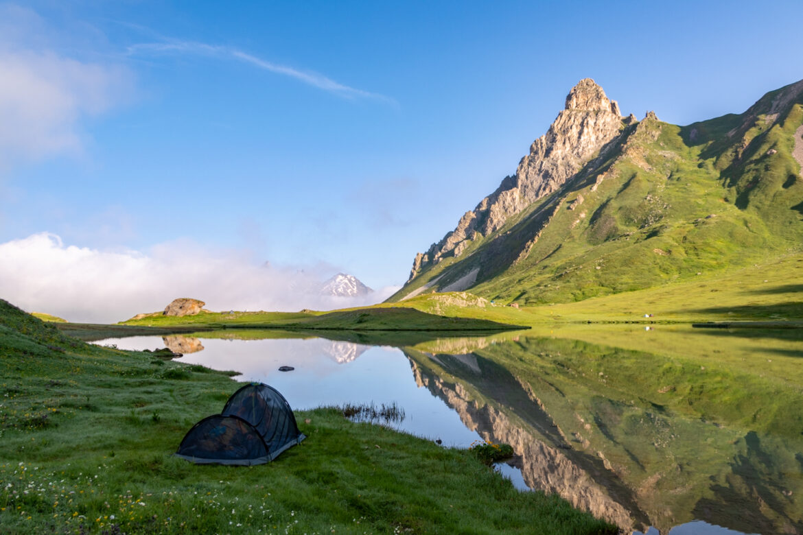 reflet de la montagne dans un lac avec une tente