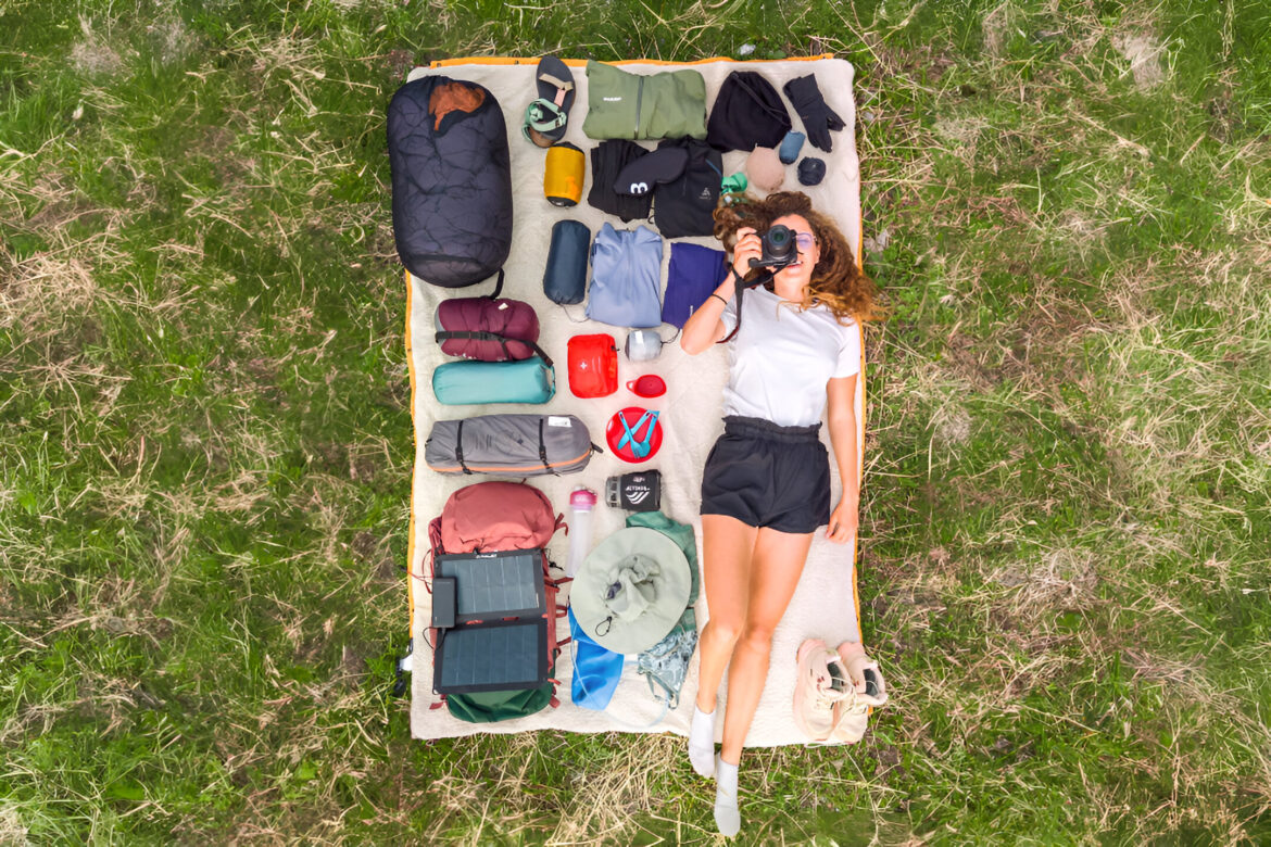 matériel de trek étalé sur une couverture avec une randonneuse vue du ciel