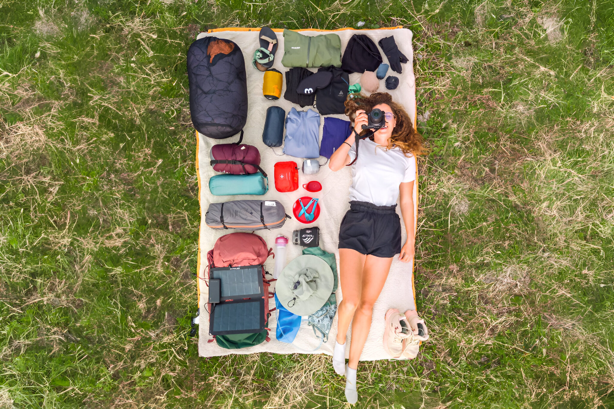 Matériel indispensable pour partir en trek et randonnée matériel de trek étalé sur une couverture avec une randonneuse vue du ciel