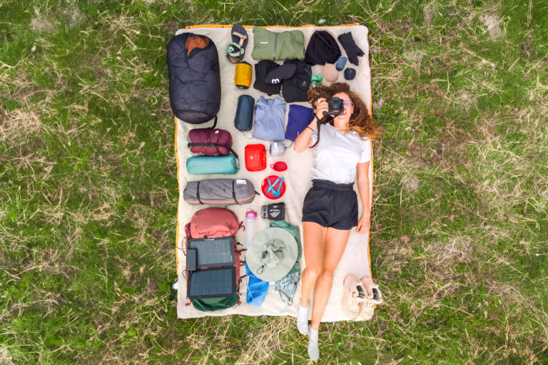 Matériel indispensable pour partir en trek et randonnée matériel de trek étalé sur une couverture avec une randonneuse vue du ciel