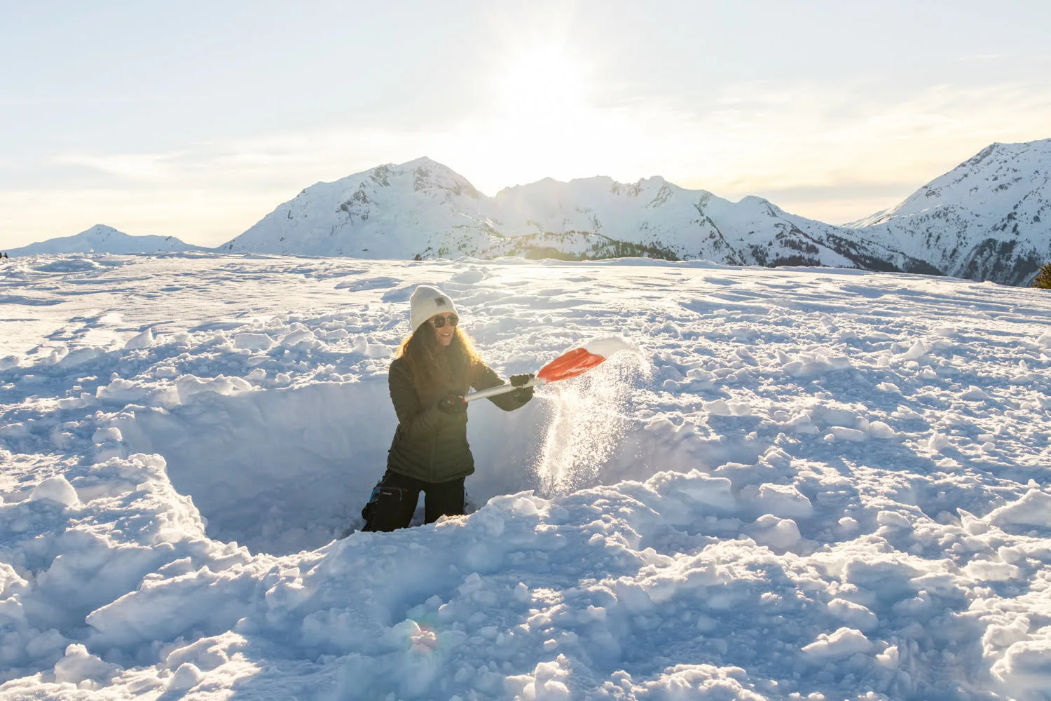 femme qui creuse un trou dans la neige pour bivouaquer