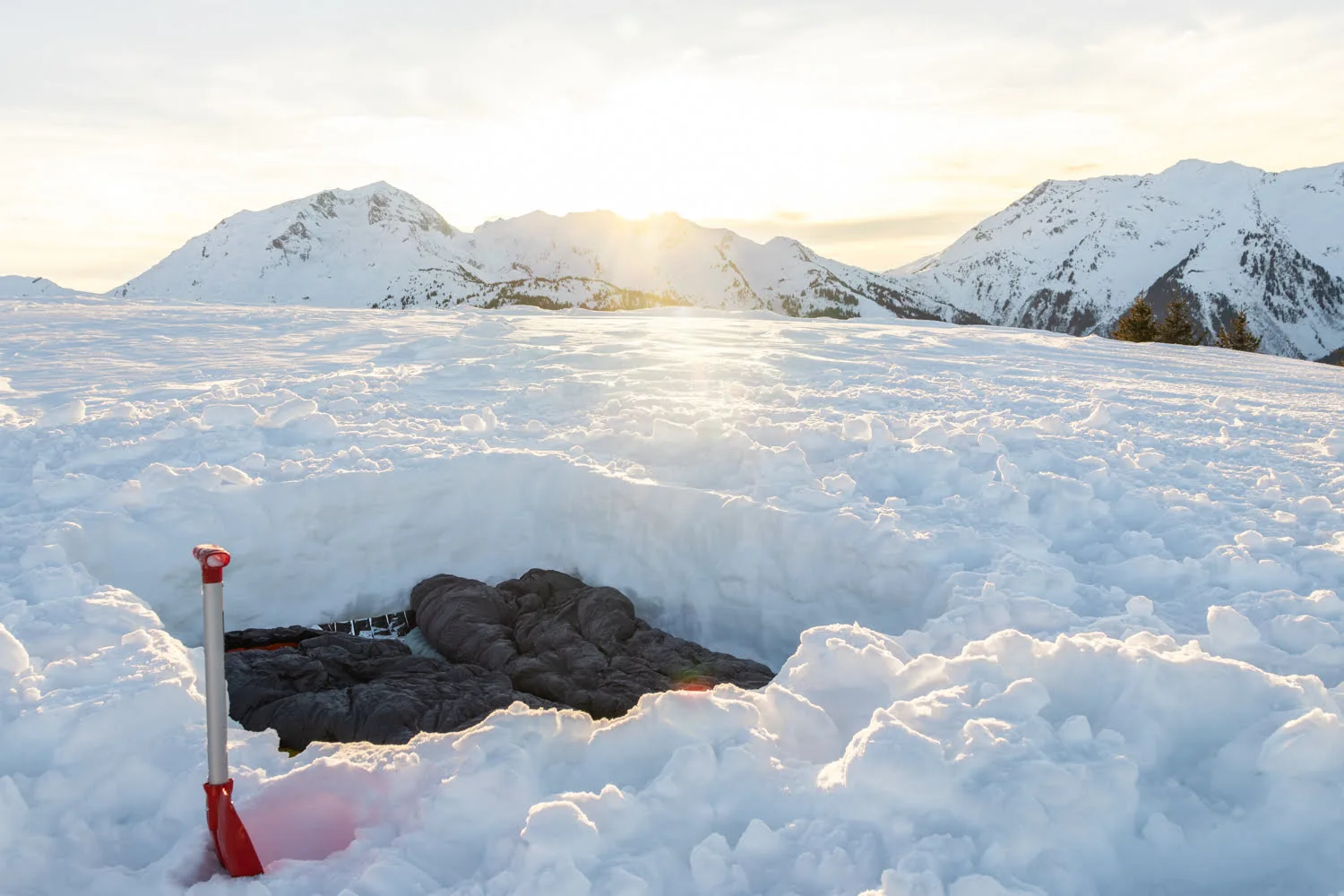 trou dans la neige pour bivouaquer avec duvet