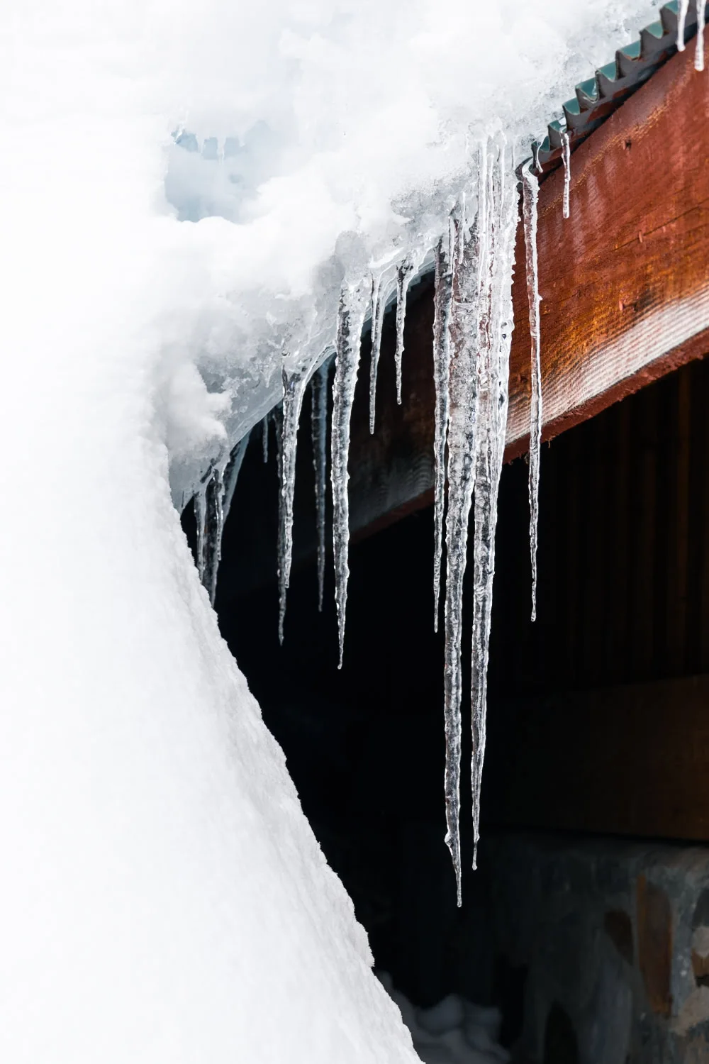 neige et stalactite qui tombent d'un toit de chalet