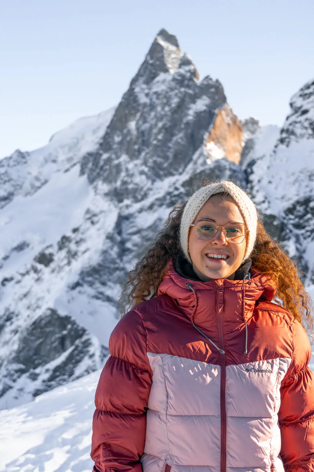 femme avec doudoune devant la montagne de la meije