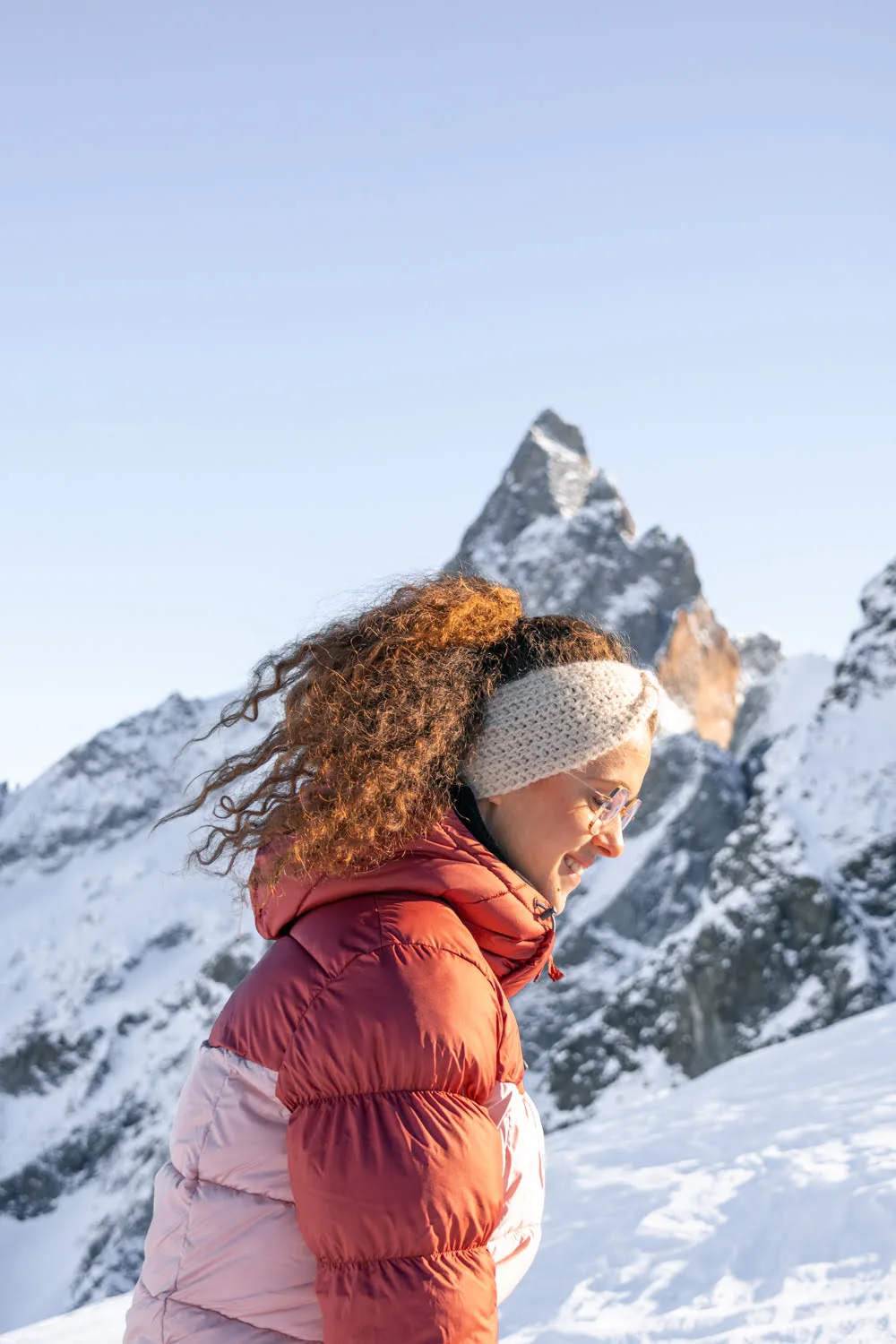 femme avec doudoune devant la montagne de la meije