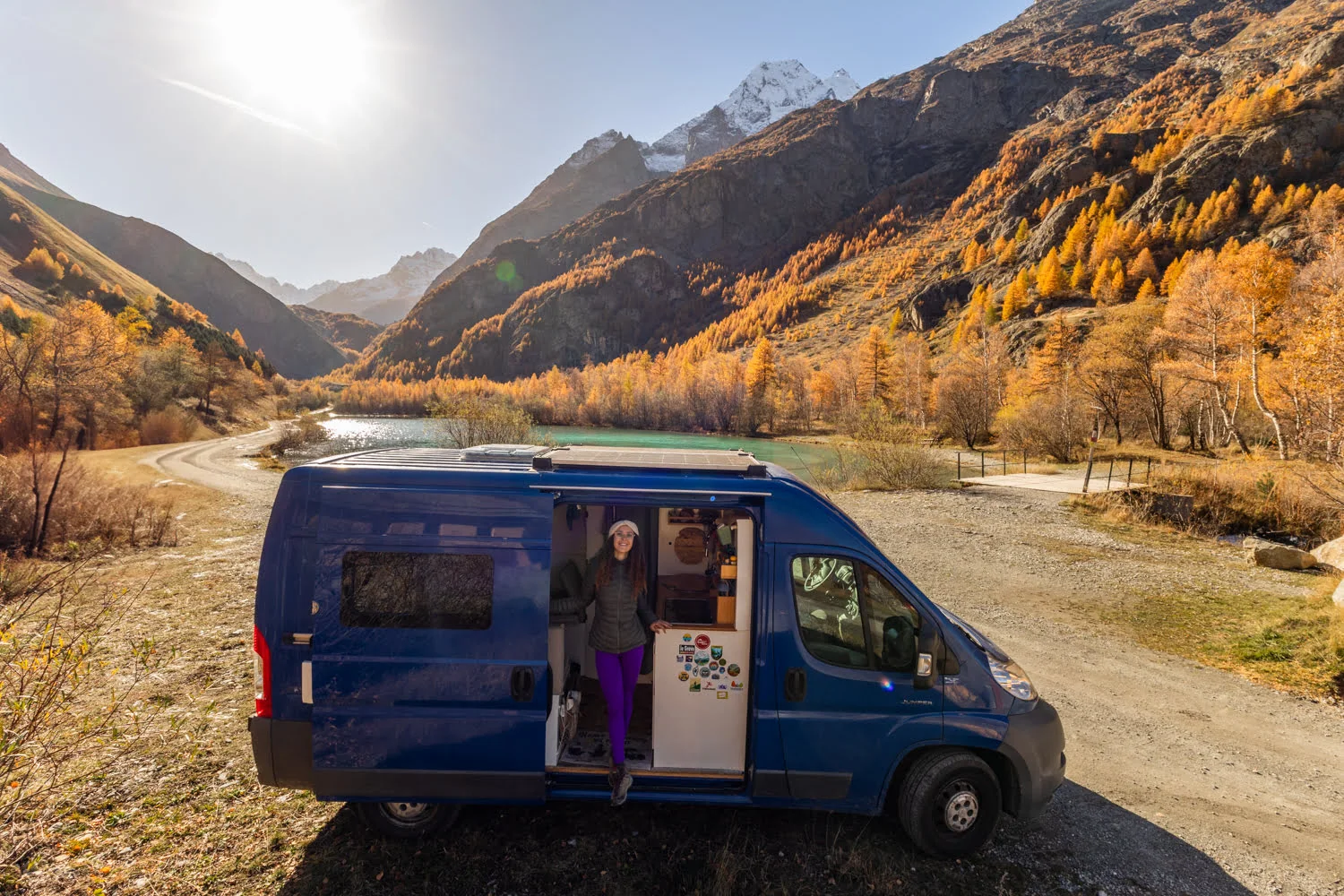 van devant un lac et une foret de mélèzes dorés