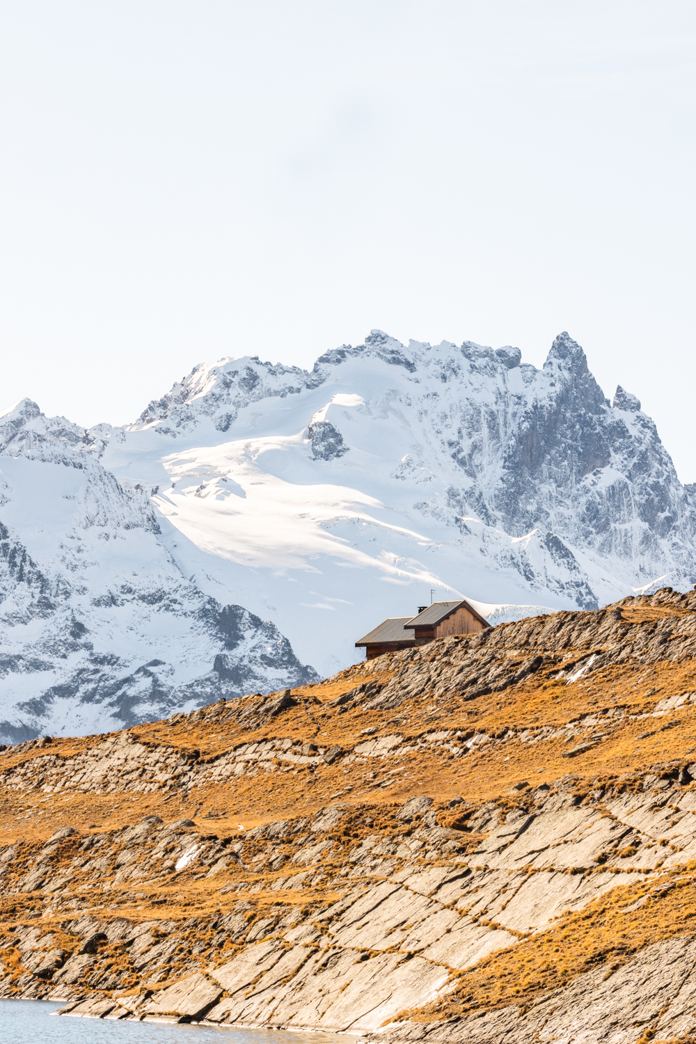 photo de la Meije avec au premier plan le refuge du Goléon niché dans l'alpage face aux sommets glacés
