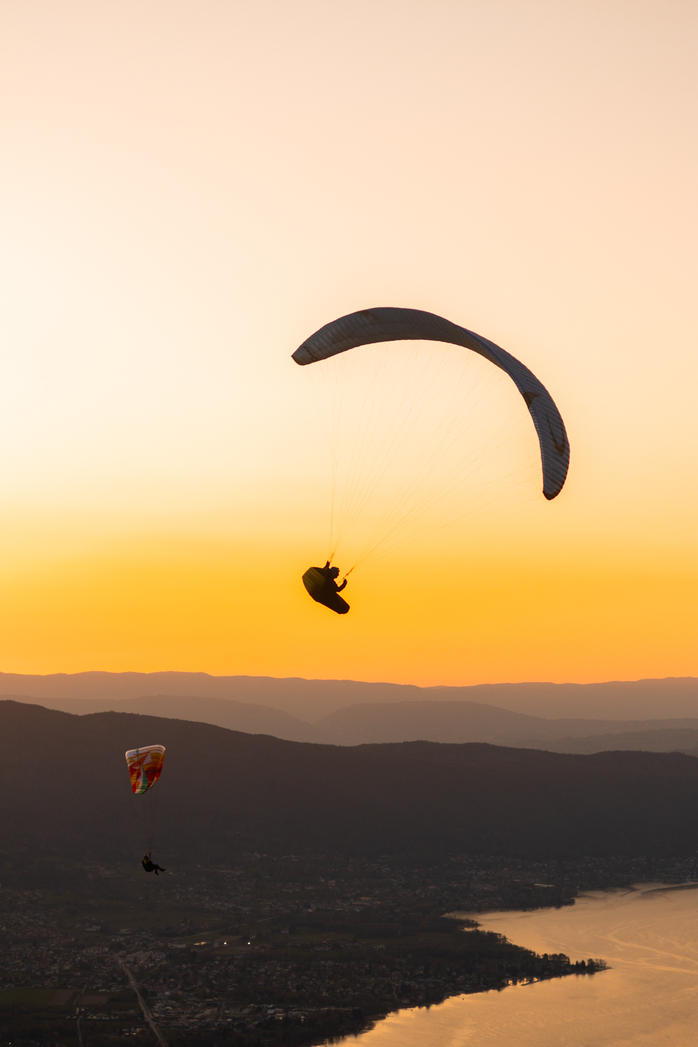 Parapente planant au-dessus du lac d'Annecy et des montagnes. Format Portrait