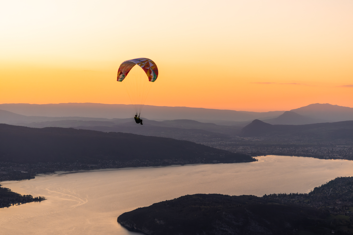 Parapente planant au-dessus du lac d'Annecy et des montagnes. Format Paysage