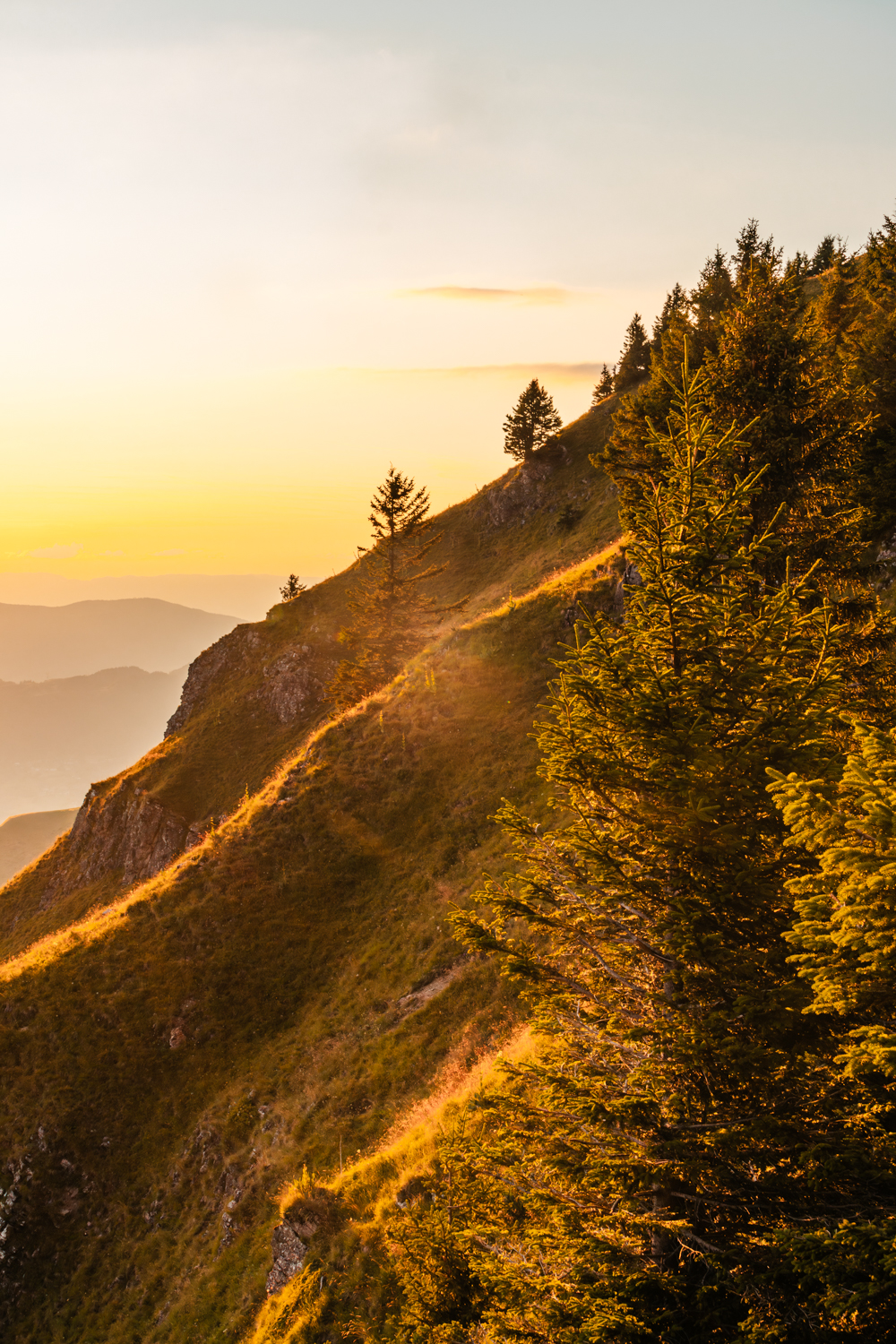 photo d'un Coucher de soleil aux teintes orangées illuminant les crêtes montagneuses à l'horizon