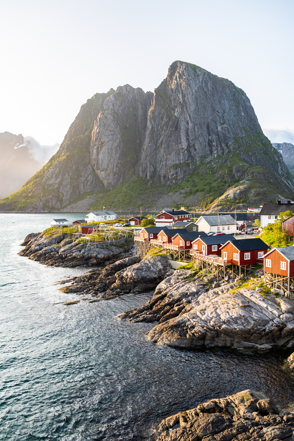 photo du village de pêcheurs de Hamnøy avec ses cabanes rouges traditionnelles au bord du fjord, dans les Lofoten. Format Portrait